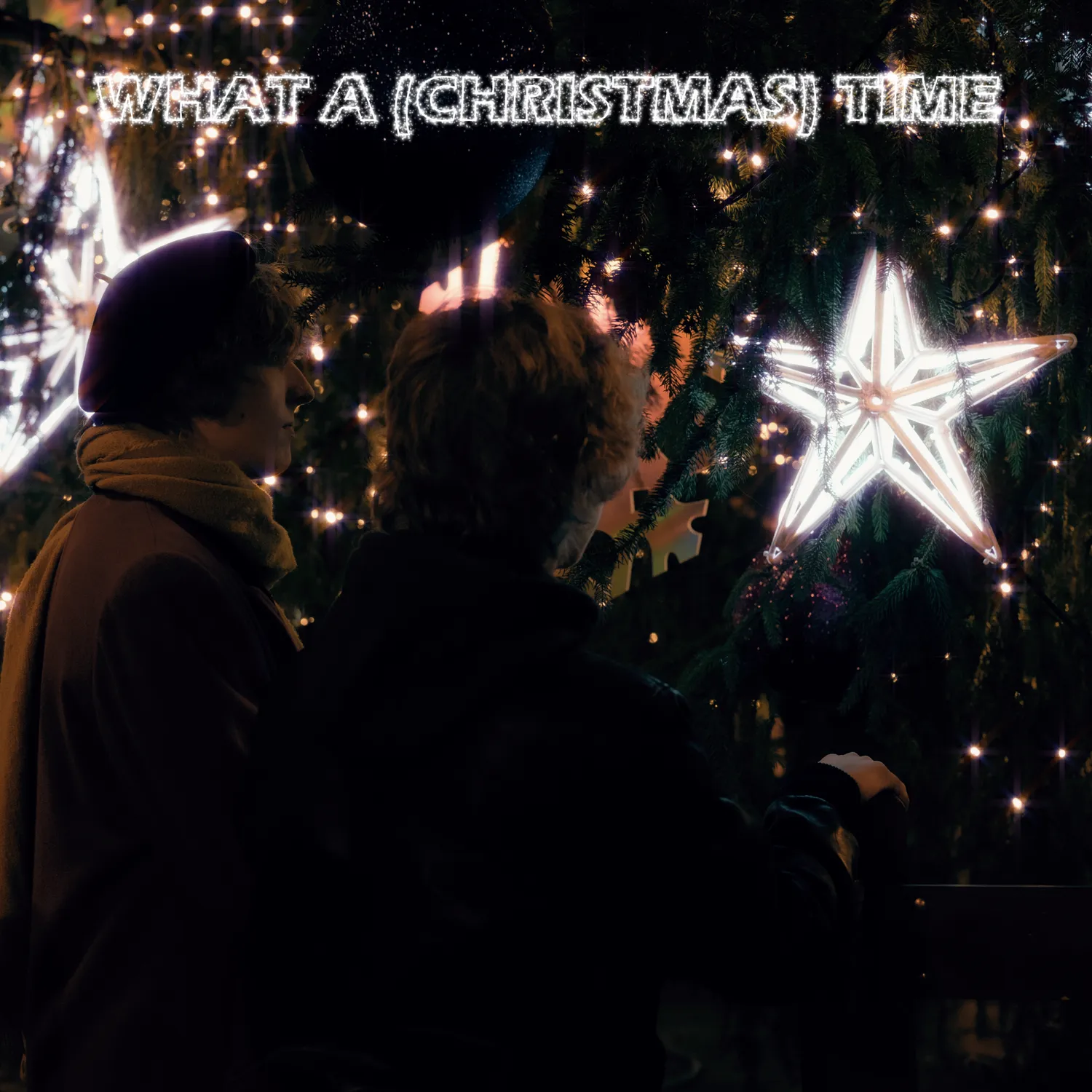 A picture taken from behind Misha and Tristan Florian as they're standing close and looking at a massive decorated Christmas tree with a big glowing star inside of it.